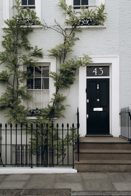 Close-up view of a white residential building on Portobello Road in Notting Hill, featuring a decorative white balustrade with turned balusters on a small balcony or porch area. The smooth, painted su